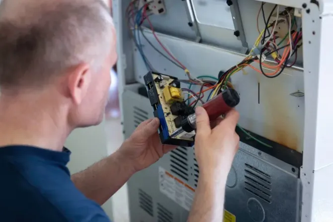 Technician repairing the control board of a kitchen oven.