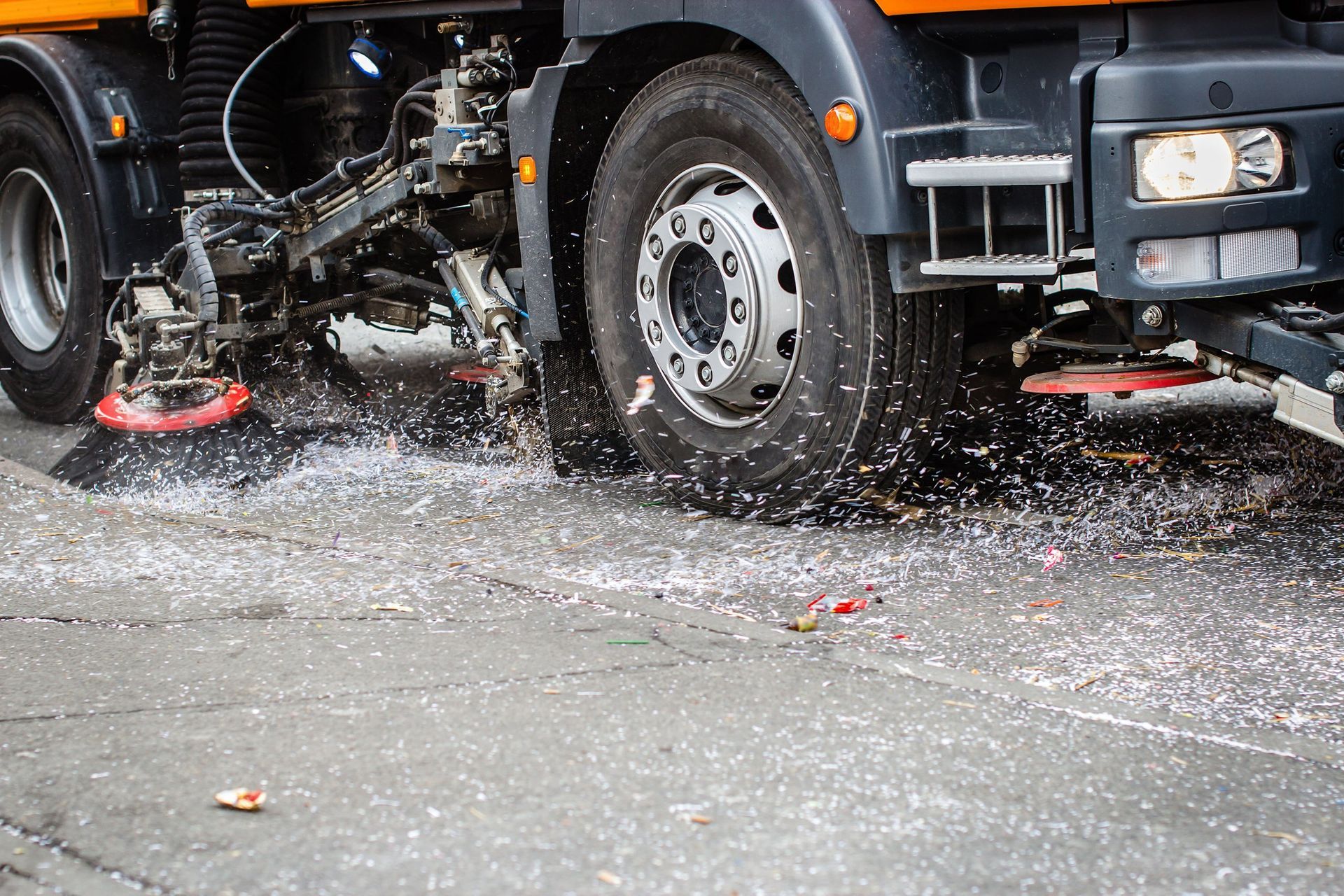A truck is cleaning the street with a broom.