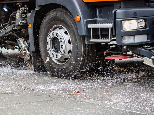 A truck is driving through a puddle of water on the road.