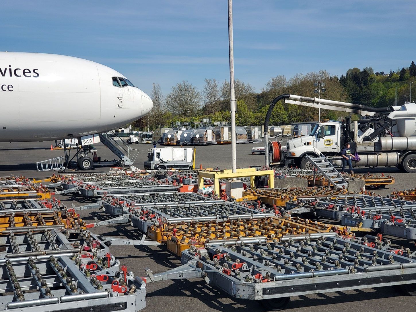 A large white airplane is parked next to a bunch of trailers.