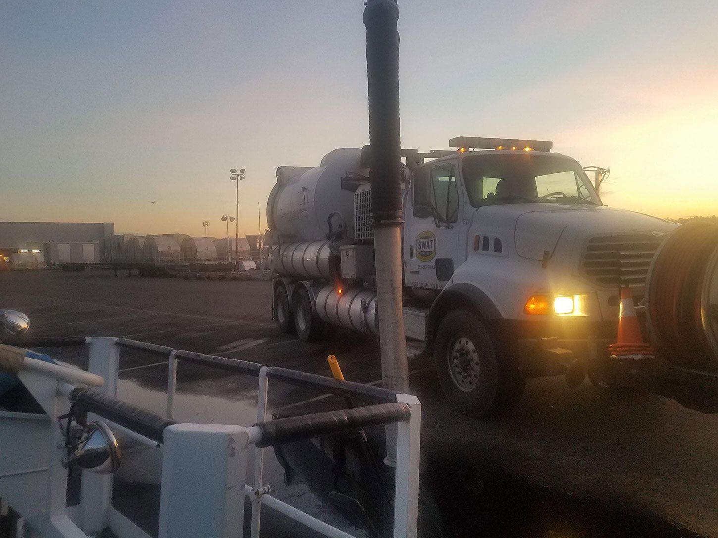 A large white truck is parked in a parking lot at sunset.