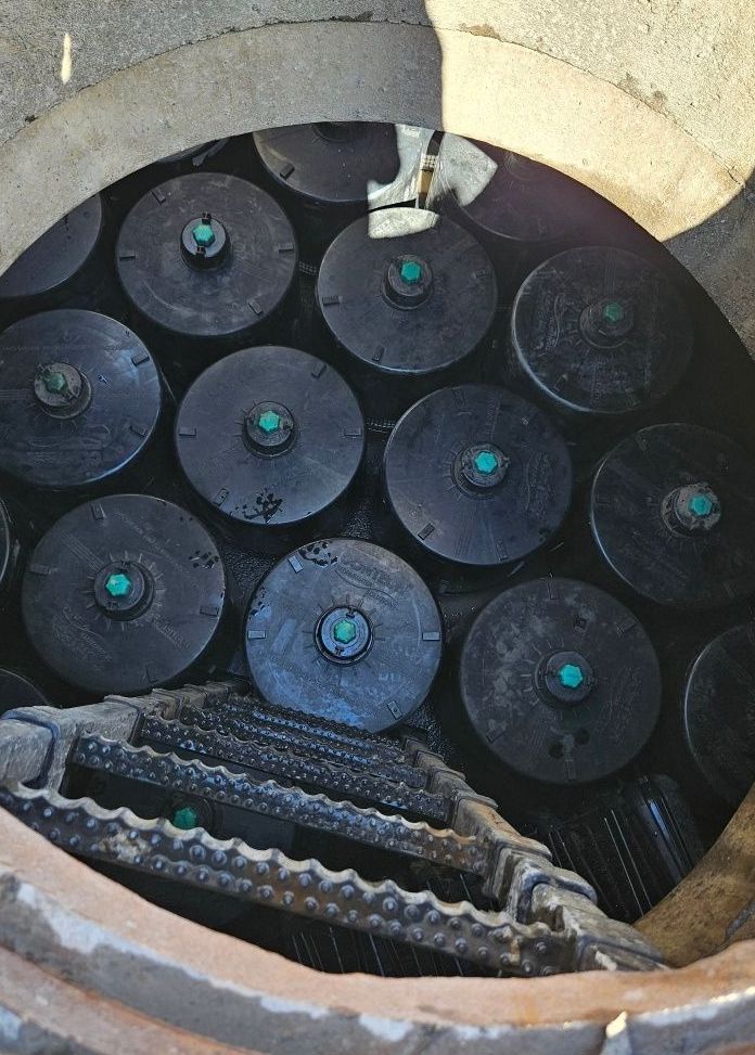 A manhole cover filled with a bunch of black circles with green labels on them.