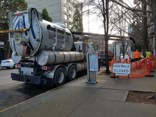 A vacuum truck is parked on the side of the road