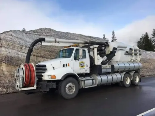 A white vacuum truck is parked on the side of the road.