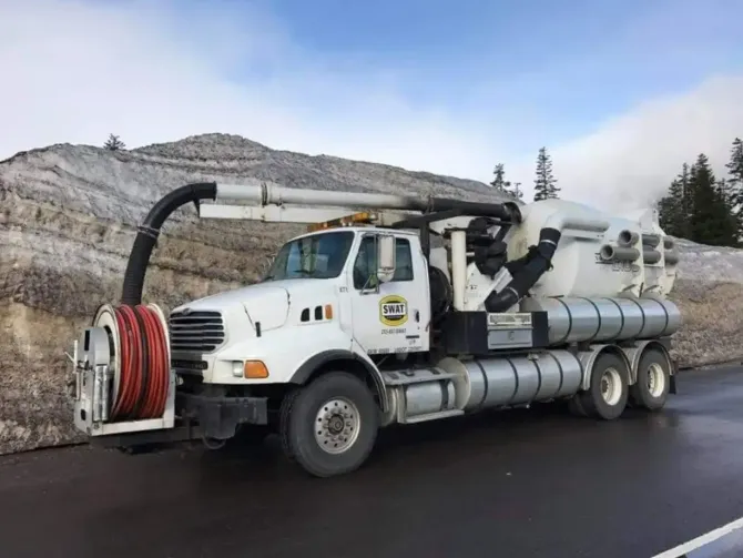 A white vacuum truck is parked on the side of the road.