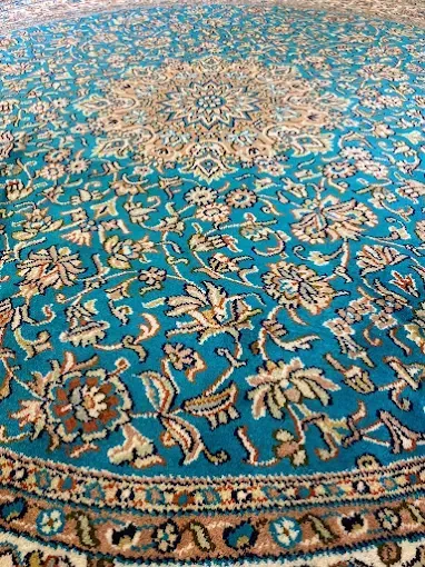 Teal and cream Persian rug with ornate floral and geometric patterns.