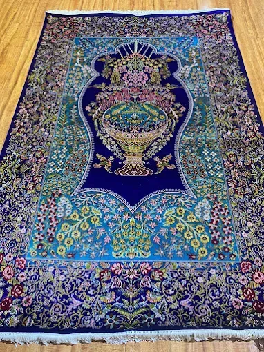 Blue Persian rug with floral motifs and central vase design.