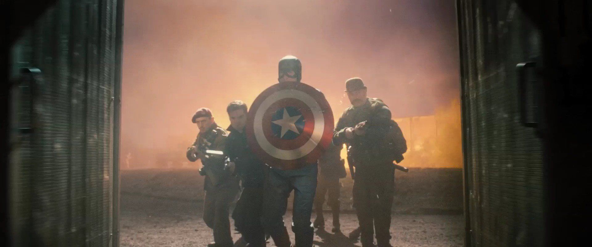 captain america entering a building with his shield in front him and soldiers behind him