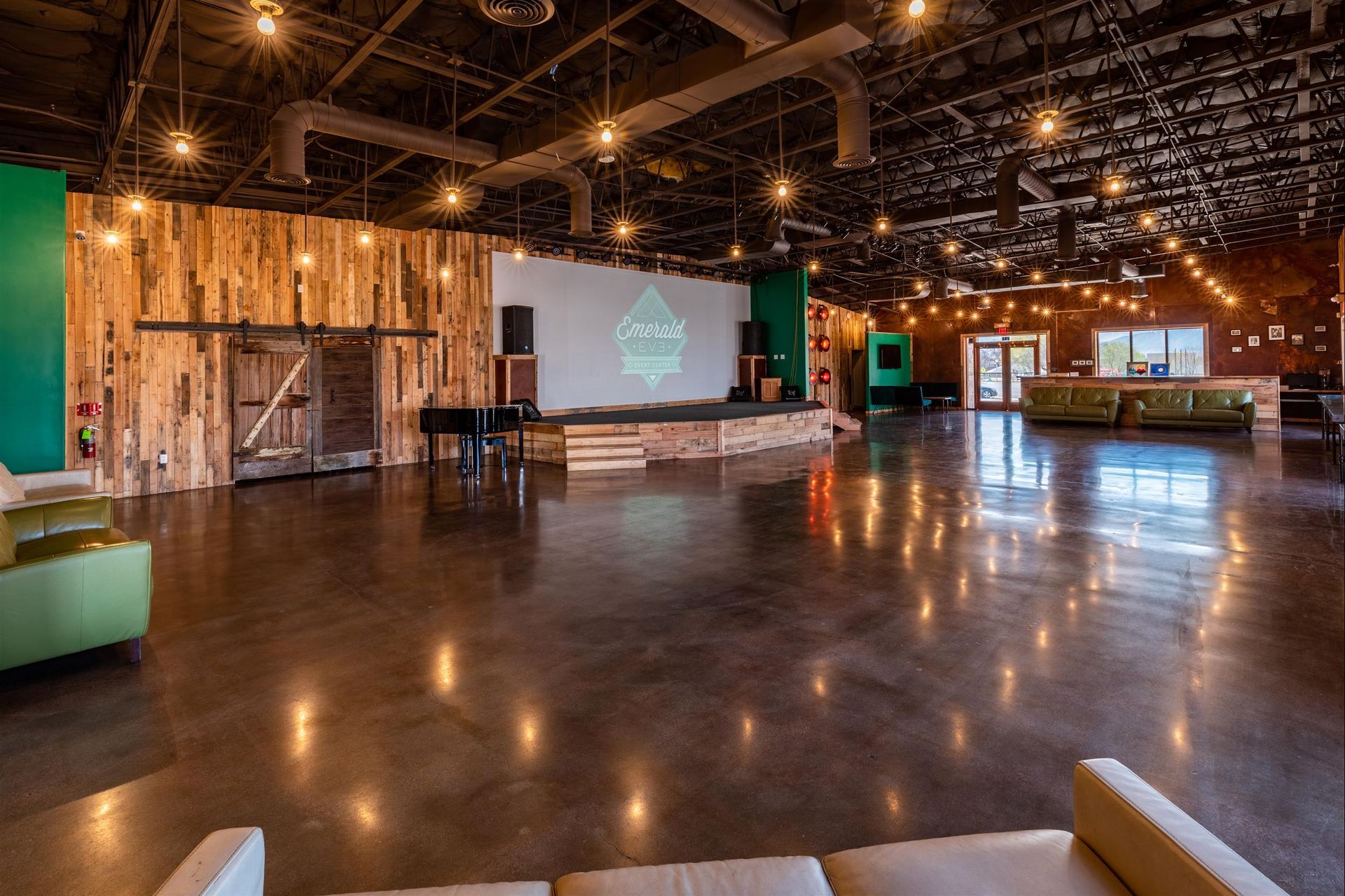 A large empty room with a projector screen and a couch.