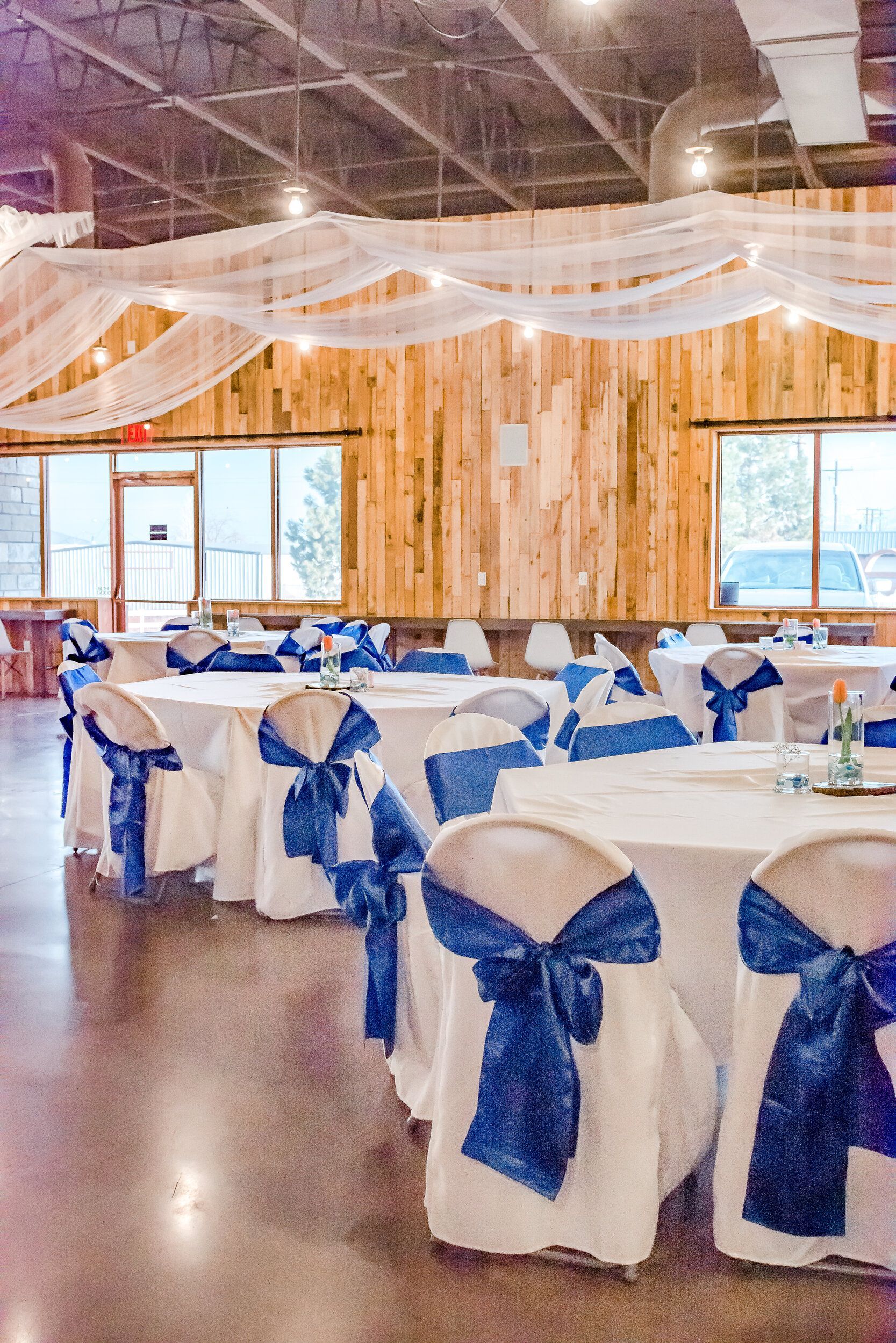 A large room with tables and chairs decorated in blue and white for a wedding reception.