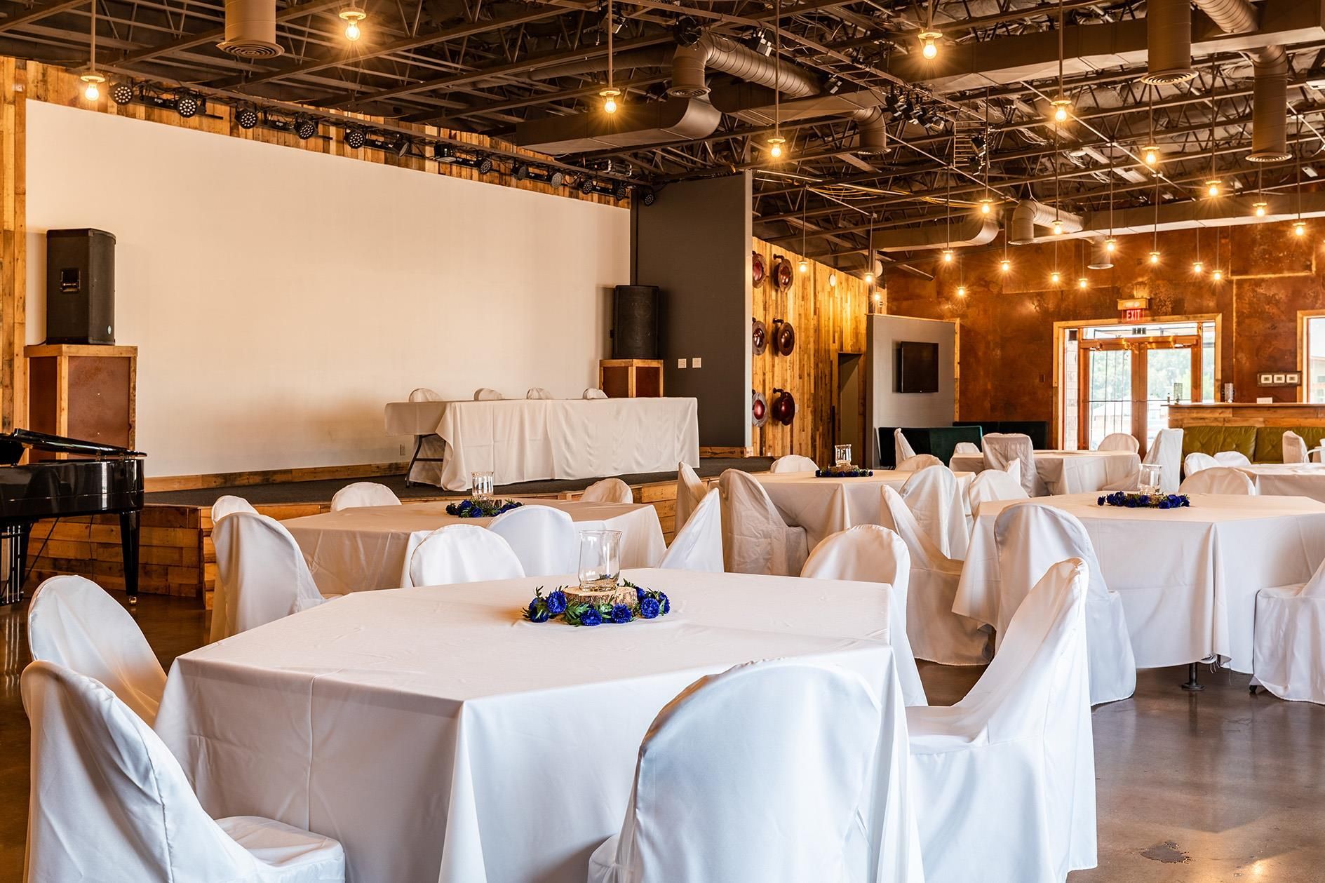 A large room with tables and chairs set up for a wedding reception.