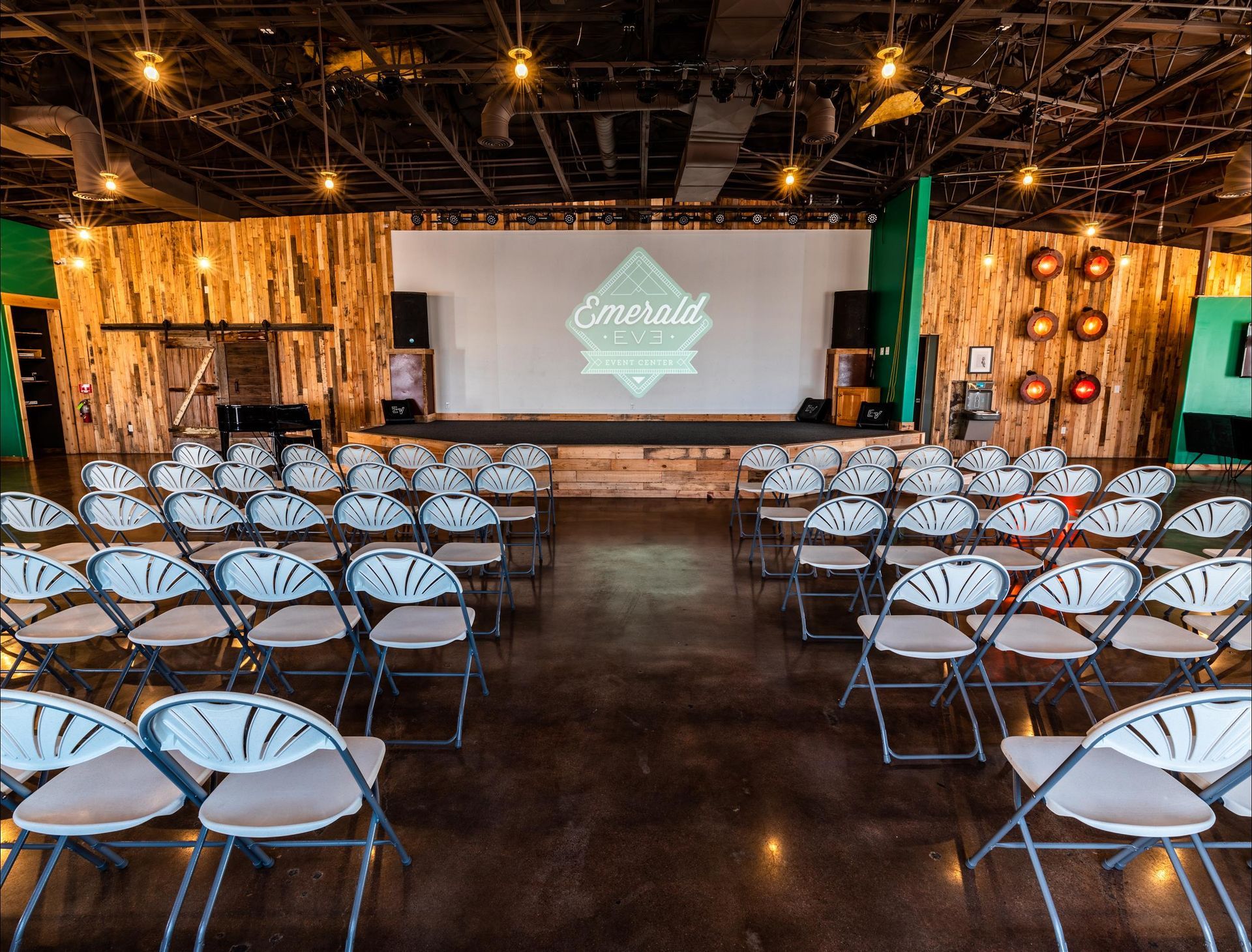 A large room filled with folding chairs and a large screen.
