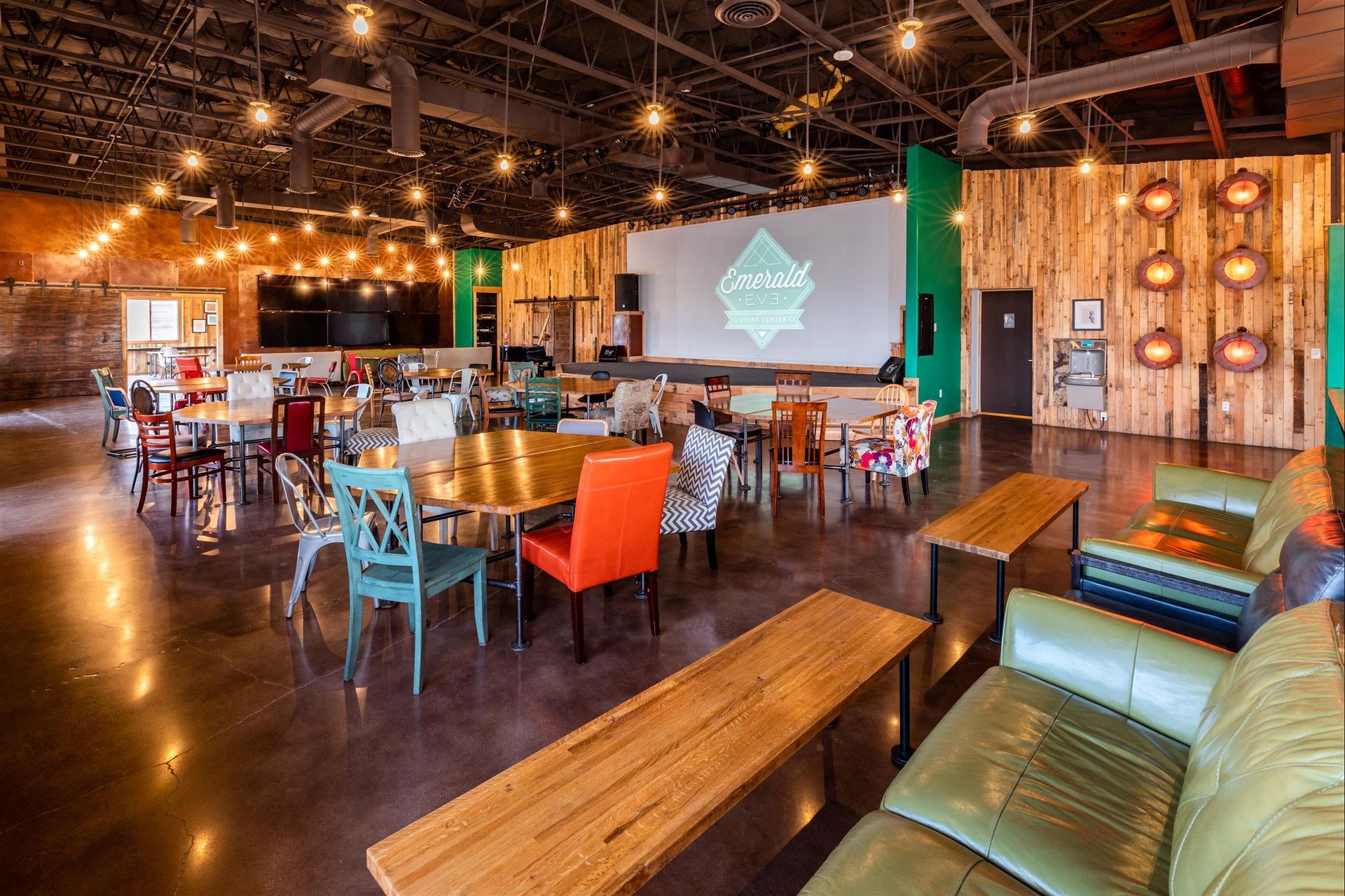 A large room filled with tables and chairs and a projector screen.