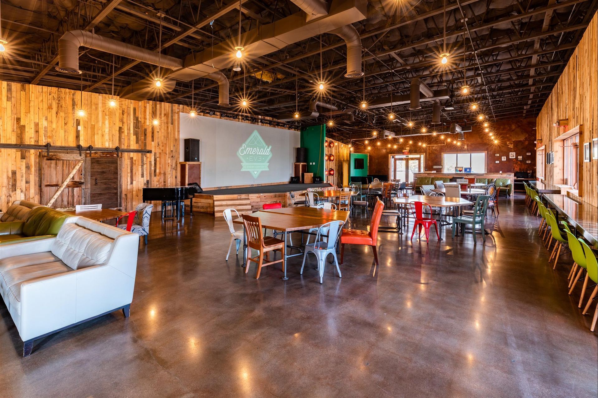 A large room with tables and chairs and a piano.
