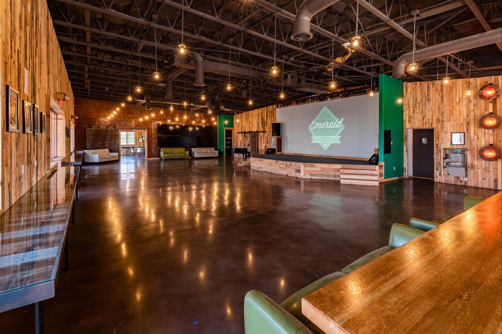 A large room with a stage and tables and chairs in it.