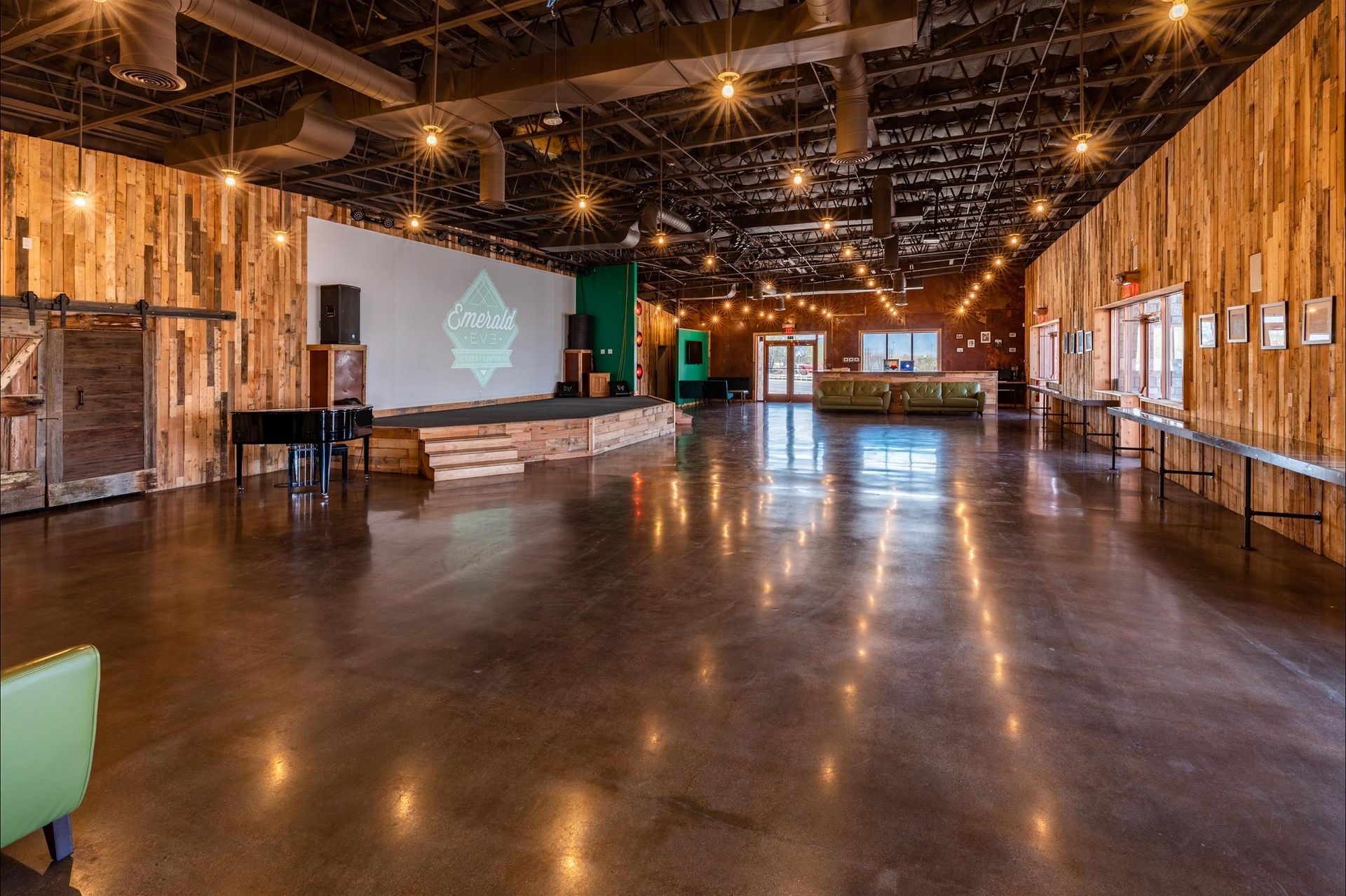A large empty room with wooden walls and a projector screen.