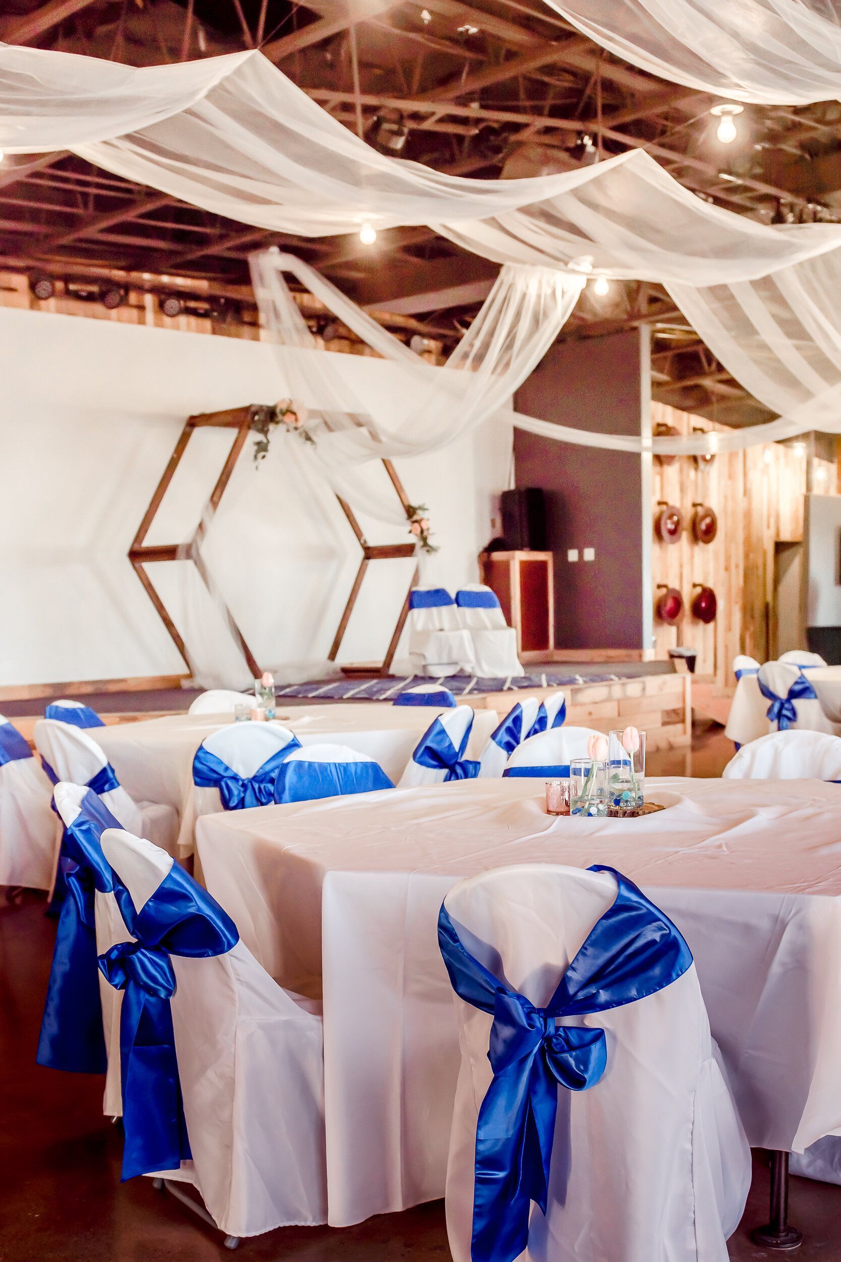 A room with tables and chairs decorated in blue and white for a wedding reception.