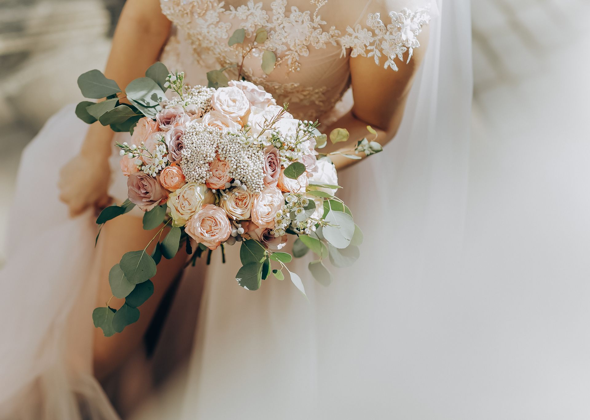 A bride in a wedding dress is holding a bouquet of flowers.