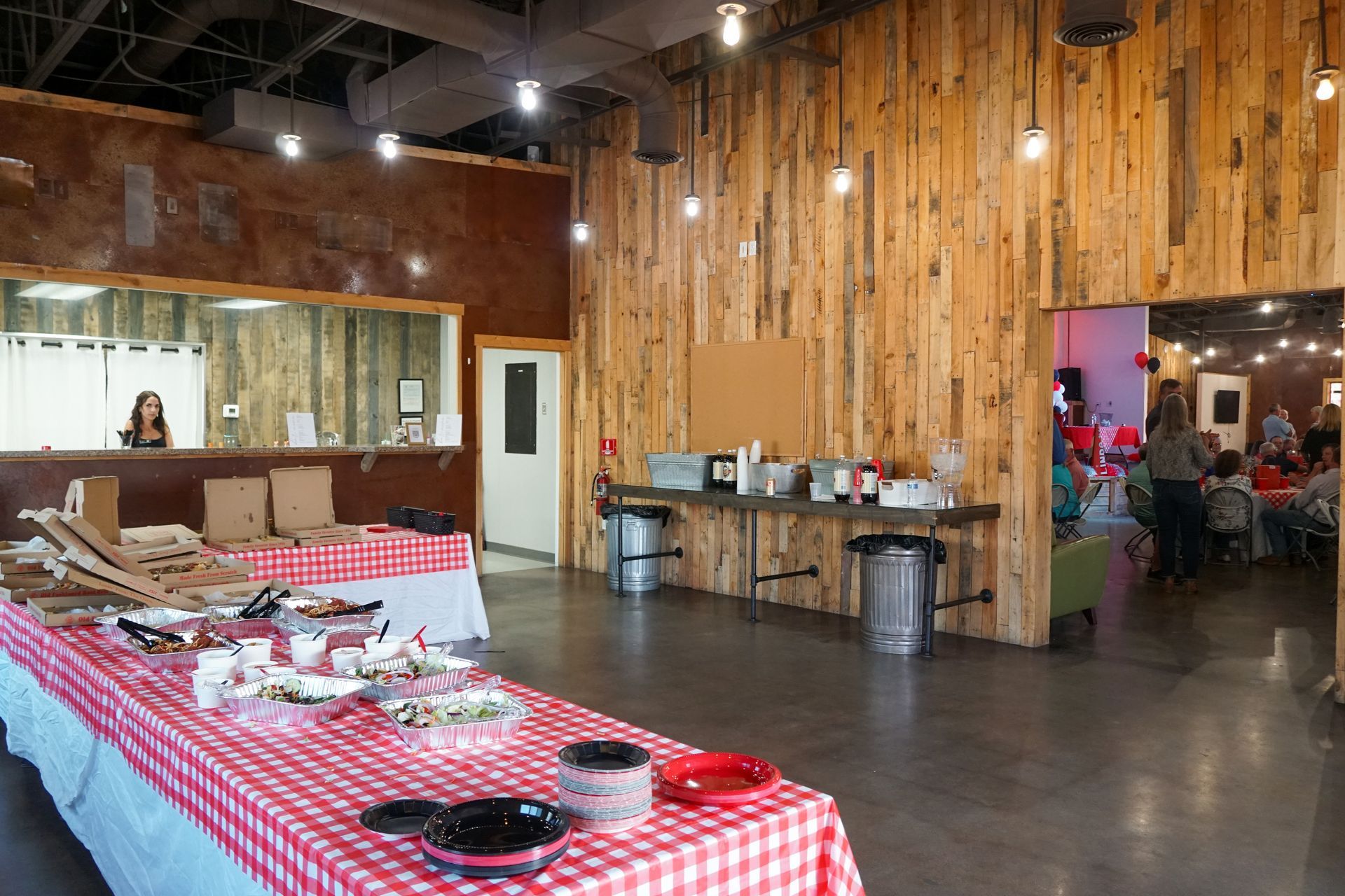 Buffet table with food, next to a wooden wall. People in a room.