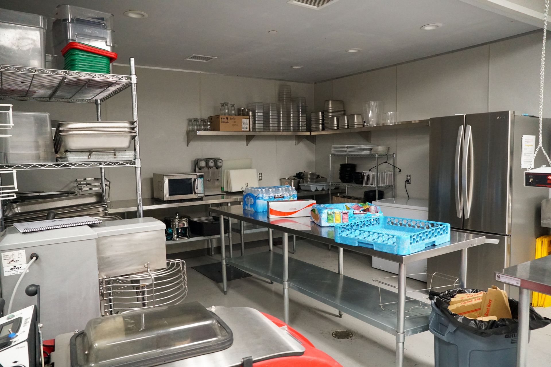 Commercial kitchen with stainless steel surfaces, shelves, and appliances.