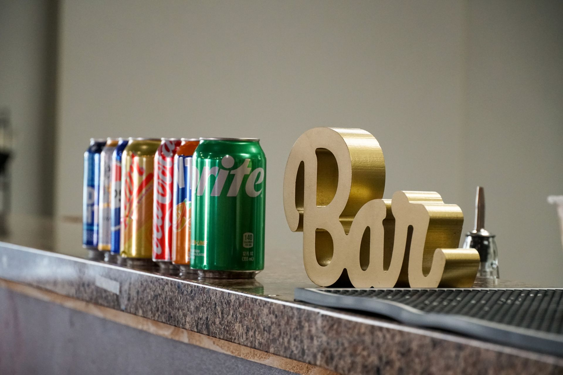 Cans of soda lined on a bar with gold 