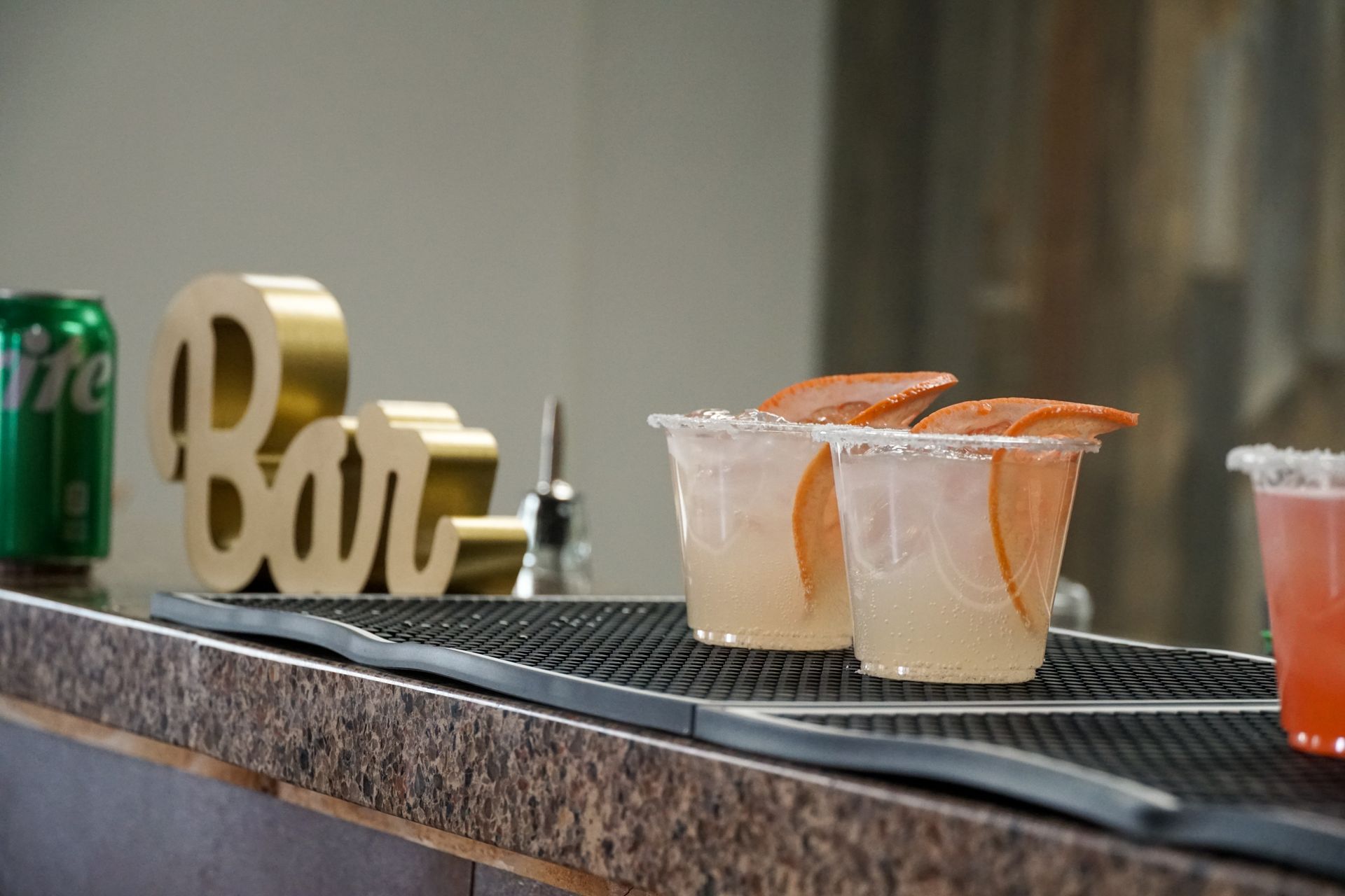 Bar with two cocktails and a can of Sprite.
