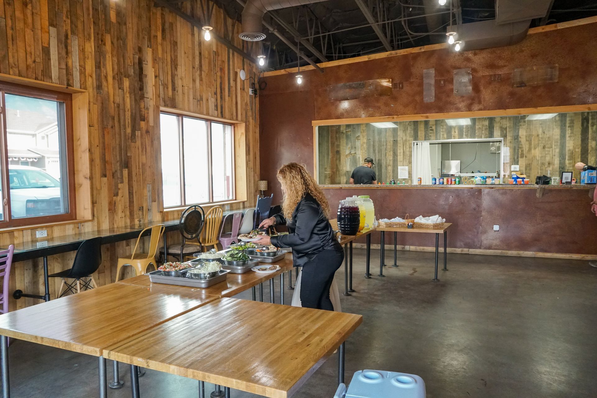 Woman preparing food at tables inside restaurant with wood and brown walls.