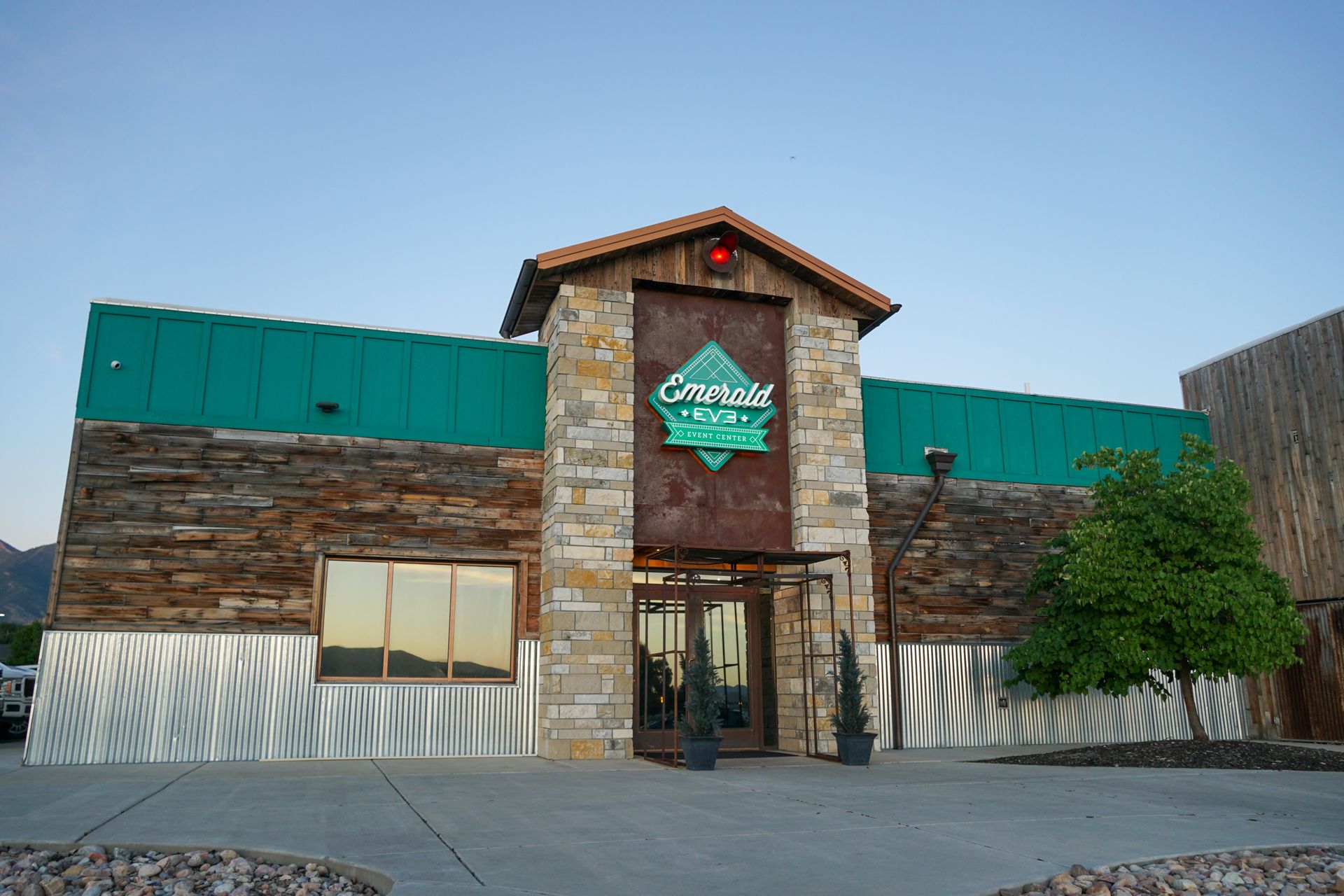 A large room with tables and chairs and a large screen on the wall.