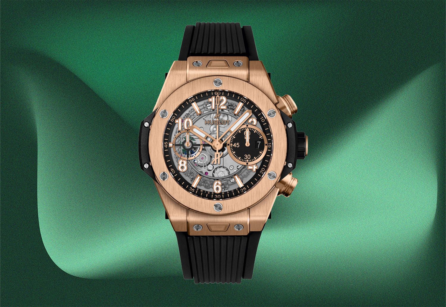 Hublot Big Bang watch with a gold case and black rubber strap on a green background.