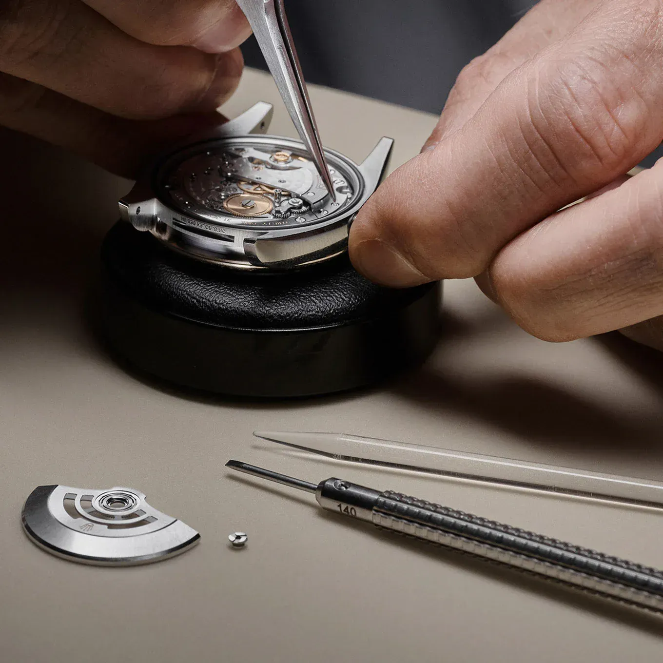 Watchmaker assembling a watch, using tools to carefully place small parts.