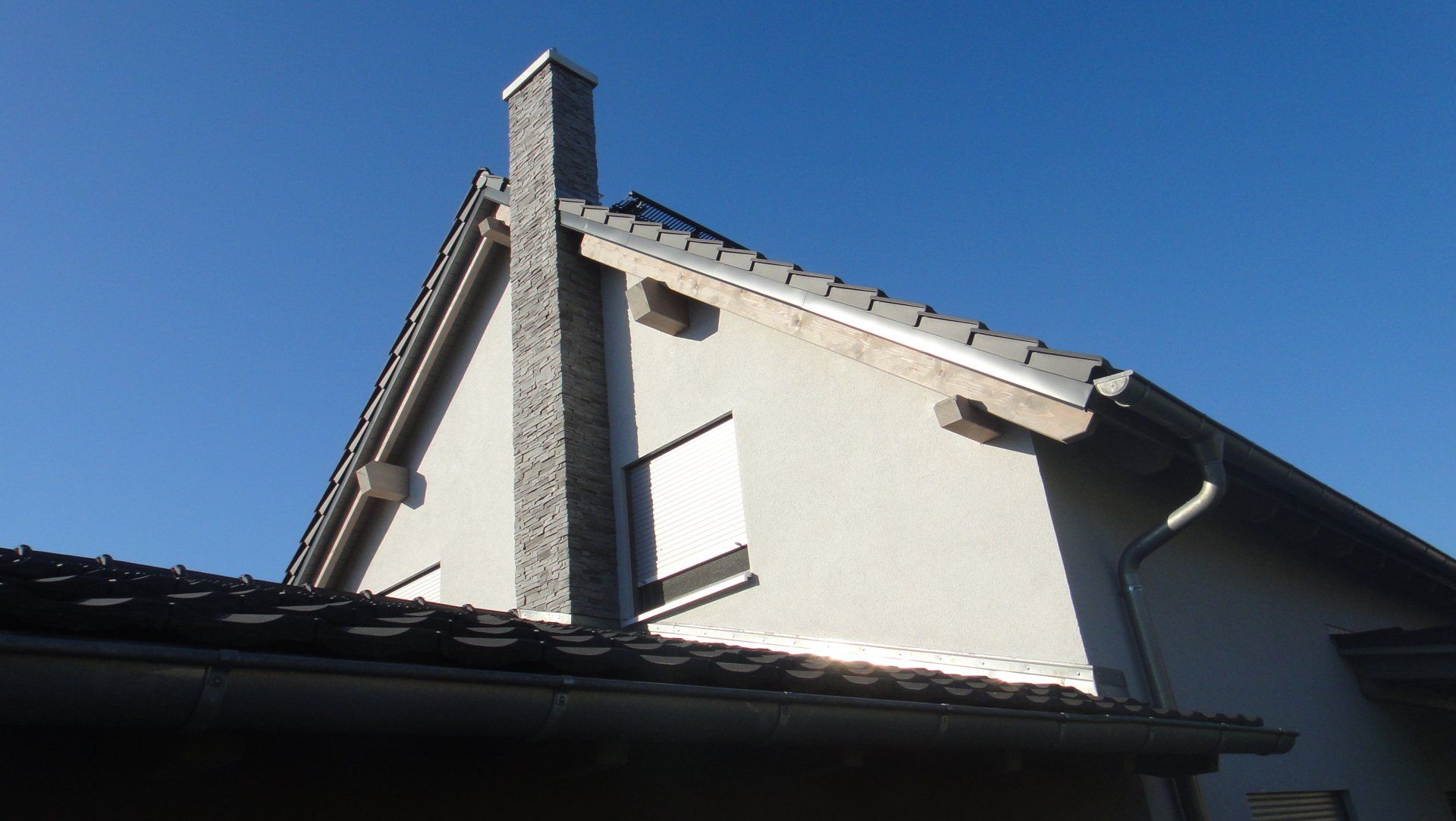 Ein Haus mit Schornstein vor blauem Himmel.