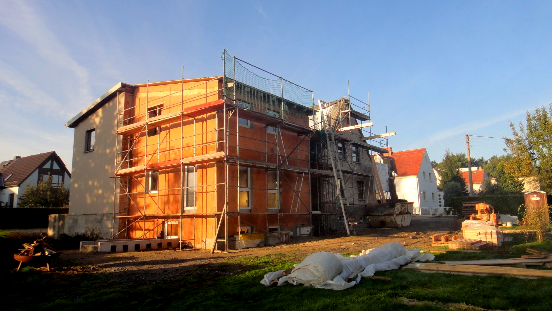 Gebäude im Umbau mit Gerüst; Backstein- und Stuckfassade, sonnige Außenlage.