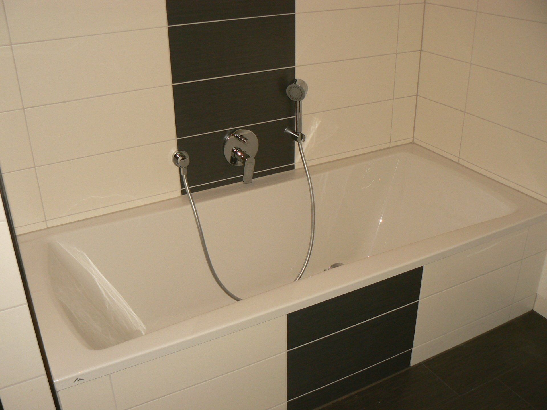 Weiße Badewanne in einem modernen Badezimmer mit schwarz-weißen Fliesenakzenten.