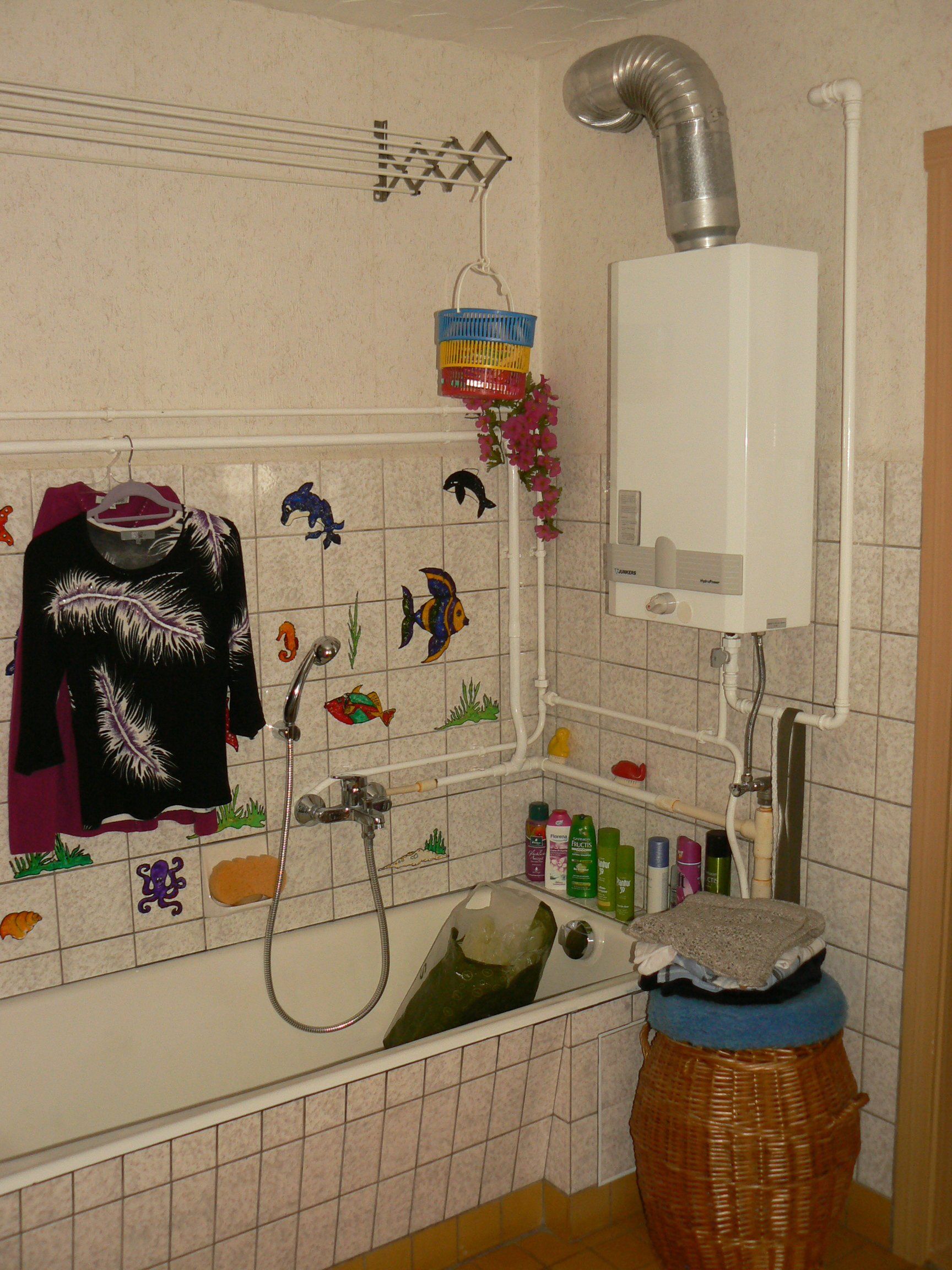 Badezimmer mit Badewanne, Warmwasserbereiter und Toilettenartikeln; dekoriert mit Fischaufklebern.