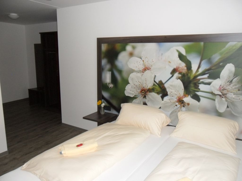 Schlafzimmer mit zwei Betten, floralem Kopfteil und Holzboden.