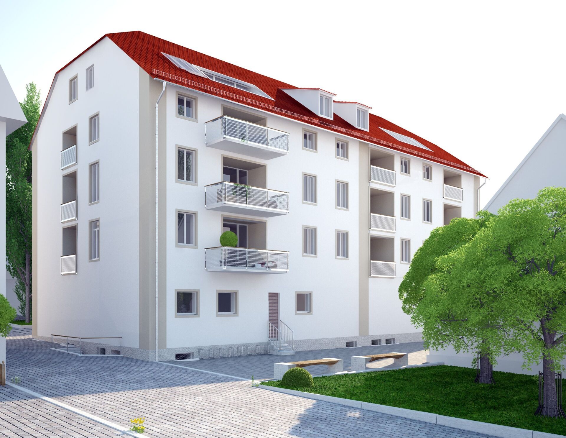 Weißes Wohnhaus mit rotem Dach, Balkonen und Kopfsteinpflasterweg.