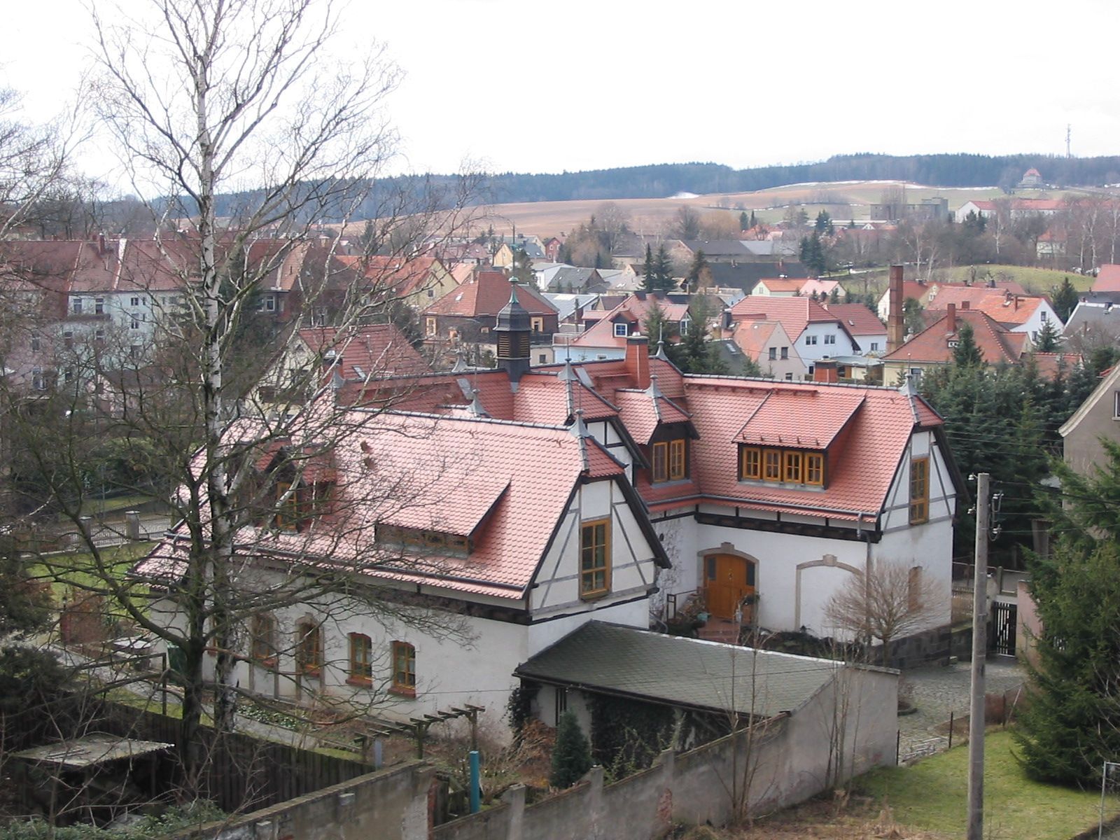 Weiße Gebäude mit roten Ziegeldächern in einer europäischen Stadt, aus der Vogelperspektive gesehen.