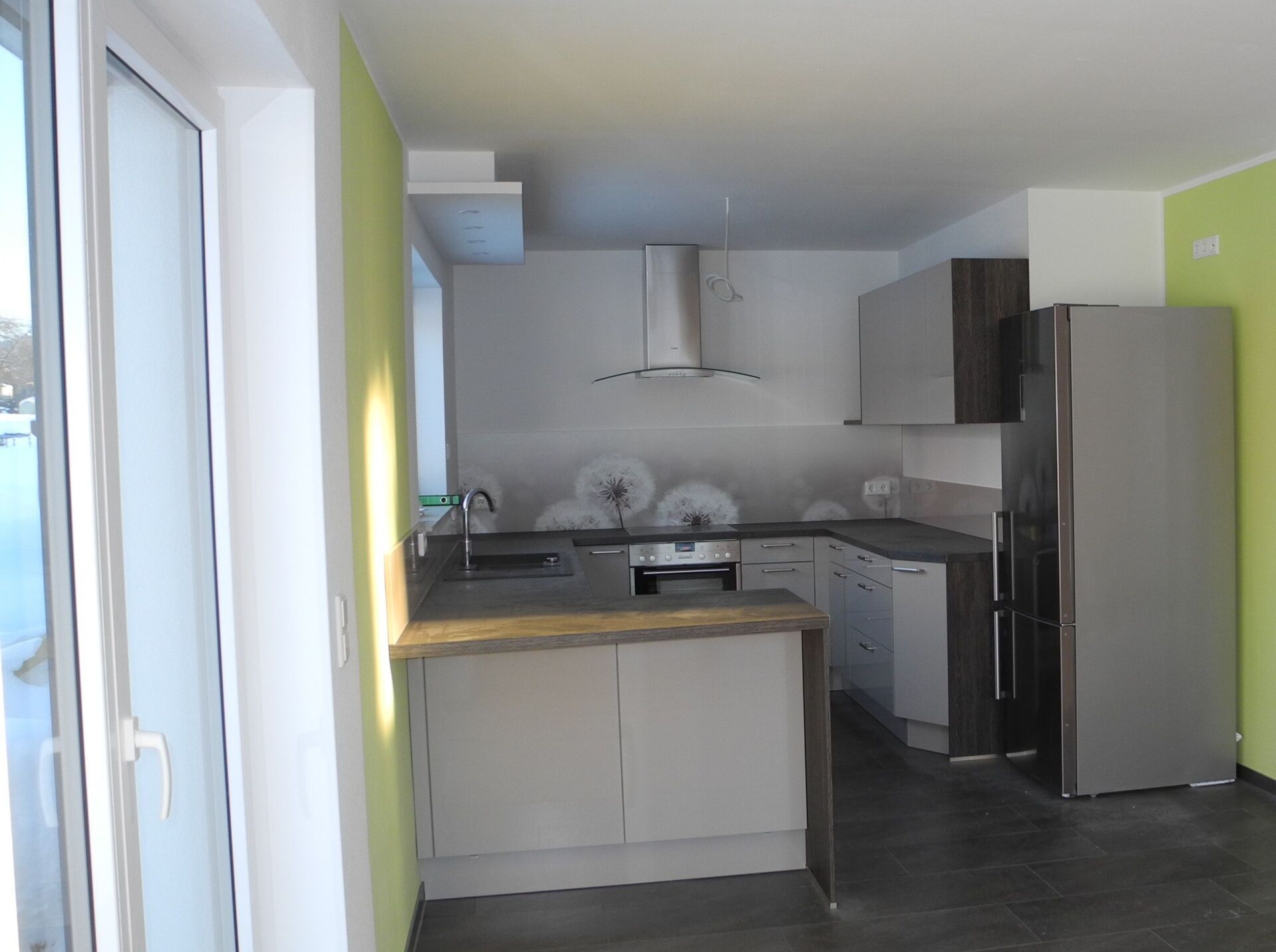 Moderne Küche mit weißen Schränken, Edelstahlgeräten und limettengrünen Akzentwänden.