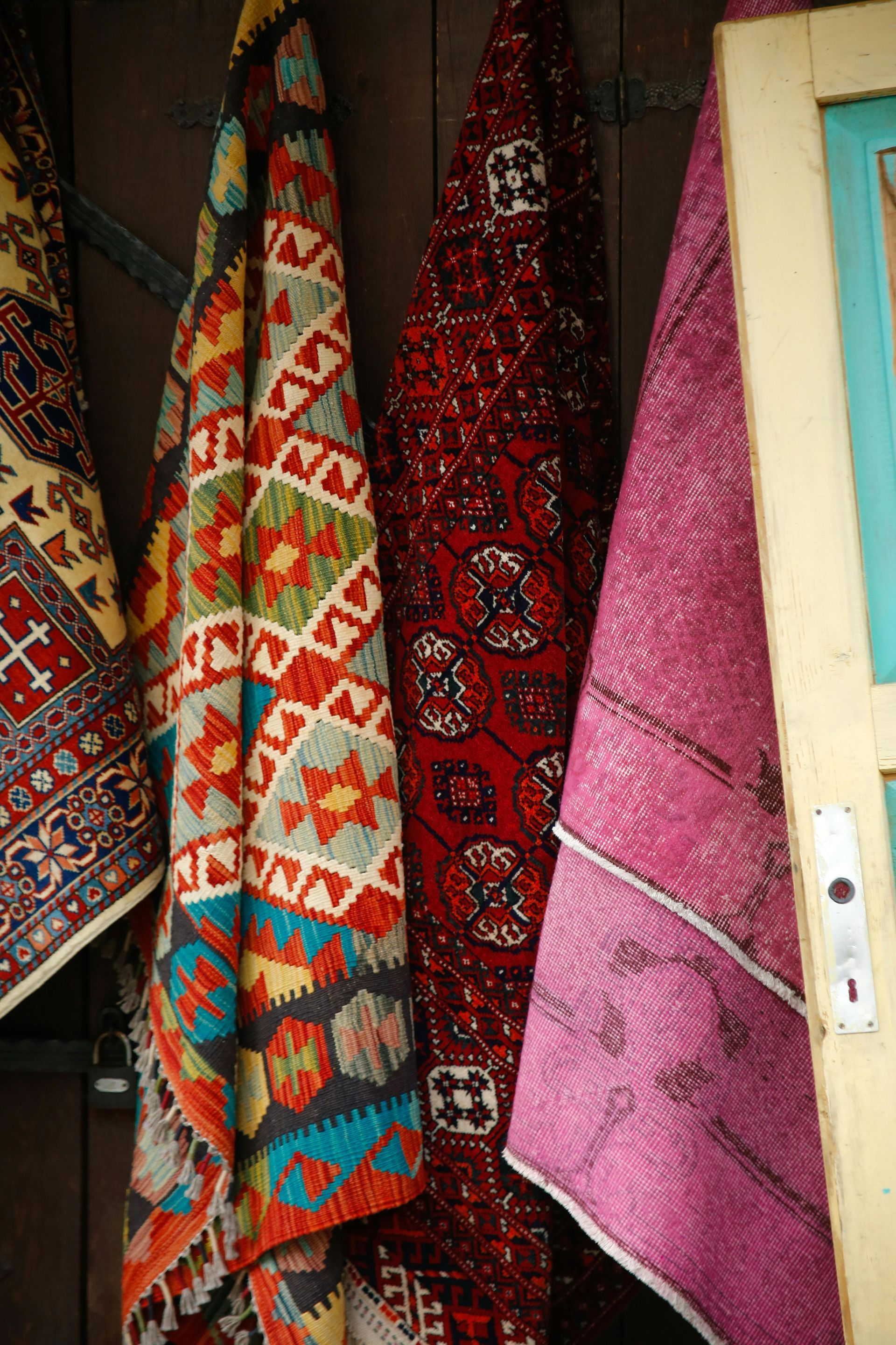 Colorful oriental rugs hanging on a wooden door.