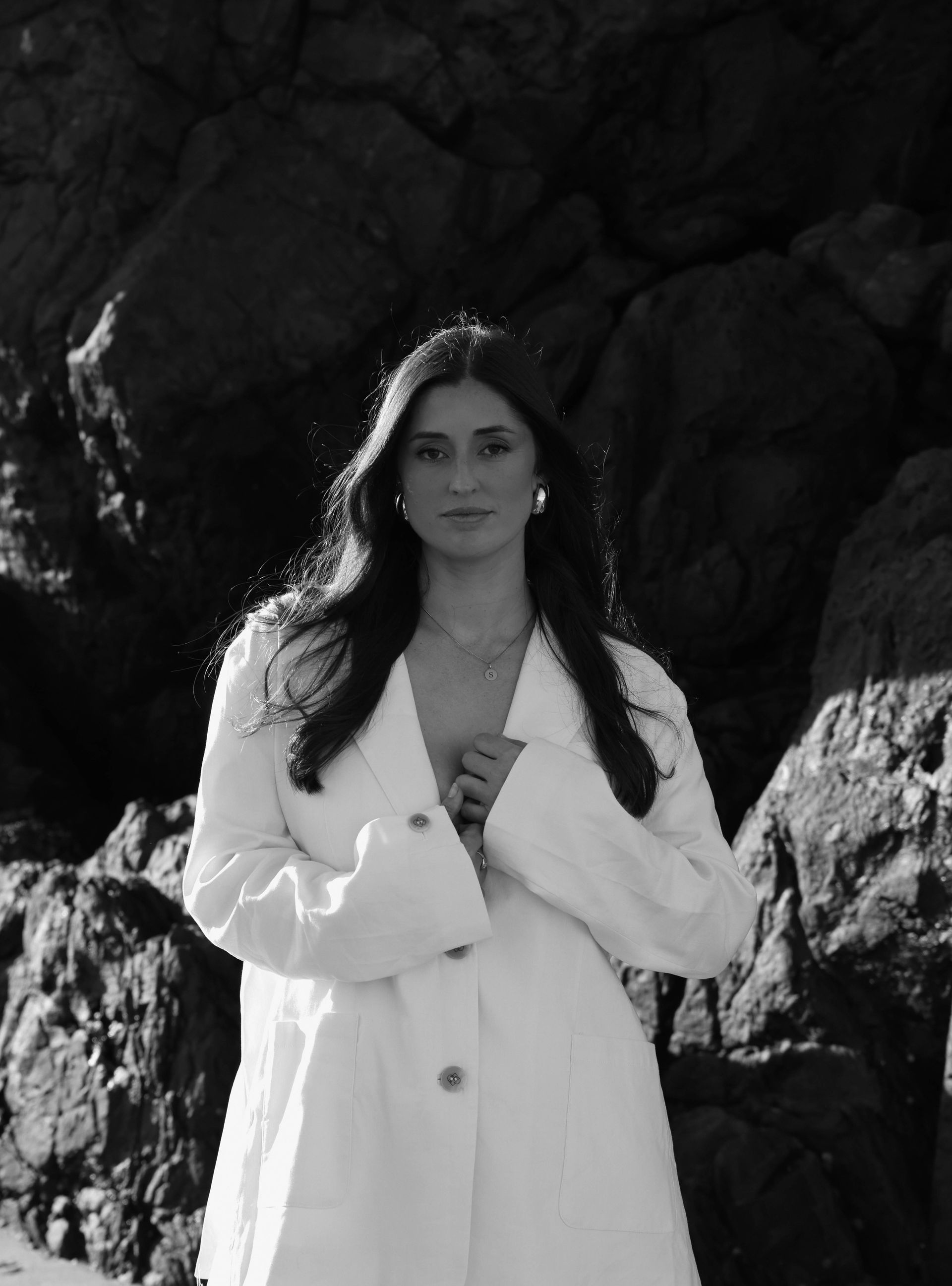 A woman in a black jumpsuit is holding a laptop computer.