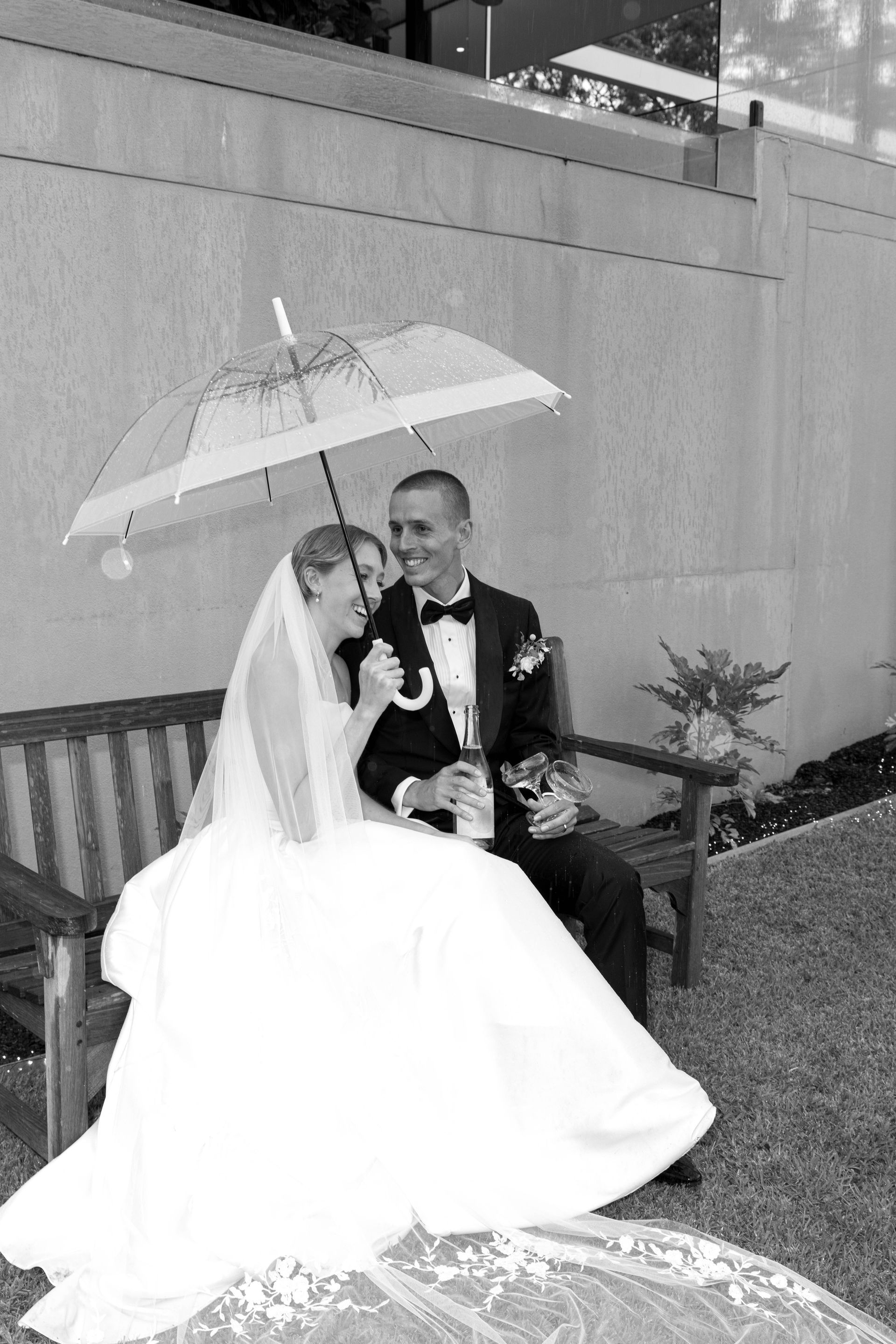 A black and white photo of a bride and groom walking down a sidewalk.