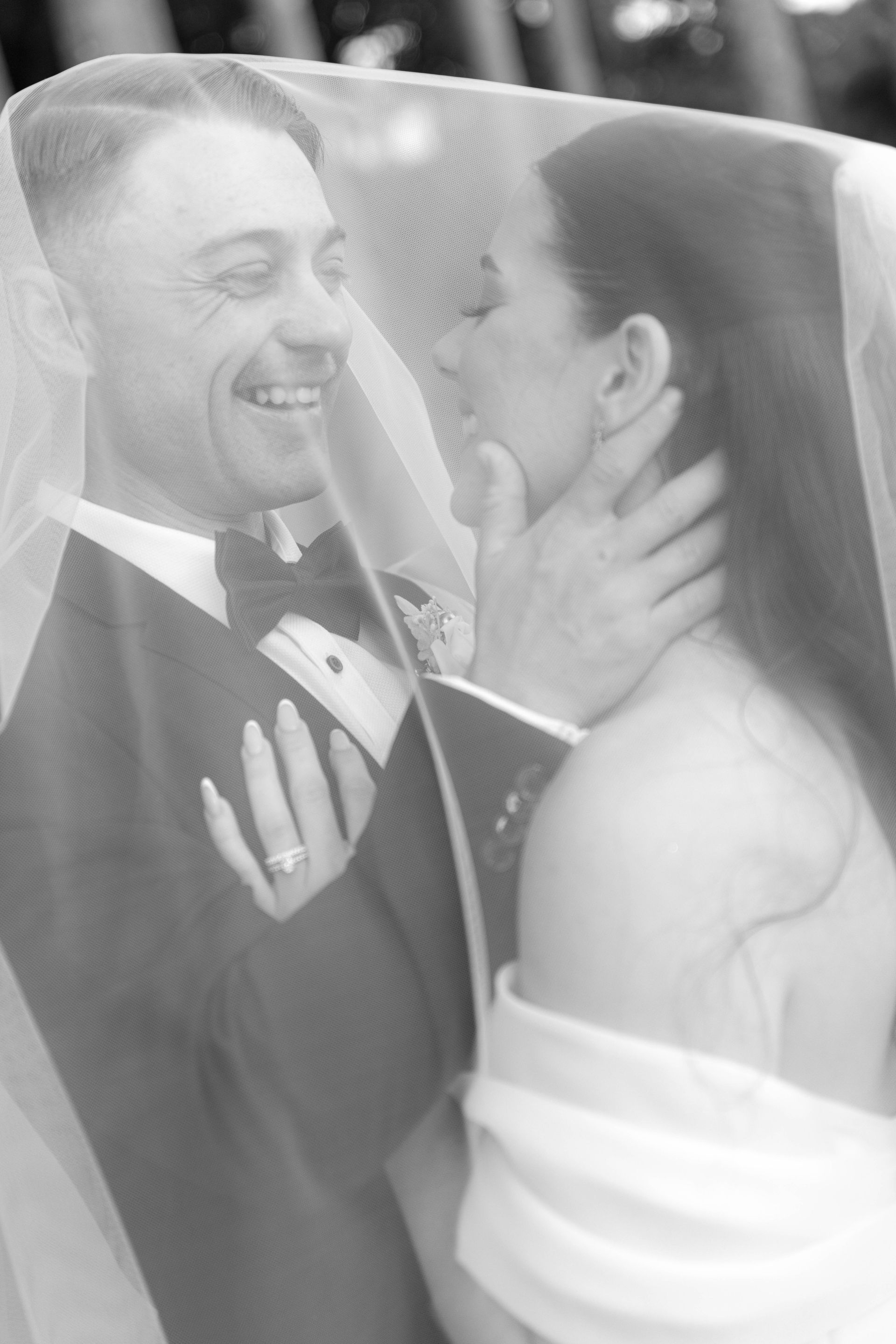 A black and white photo of a bride and groom walking down a sidewalk.