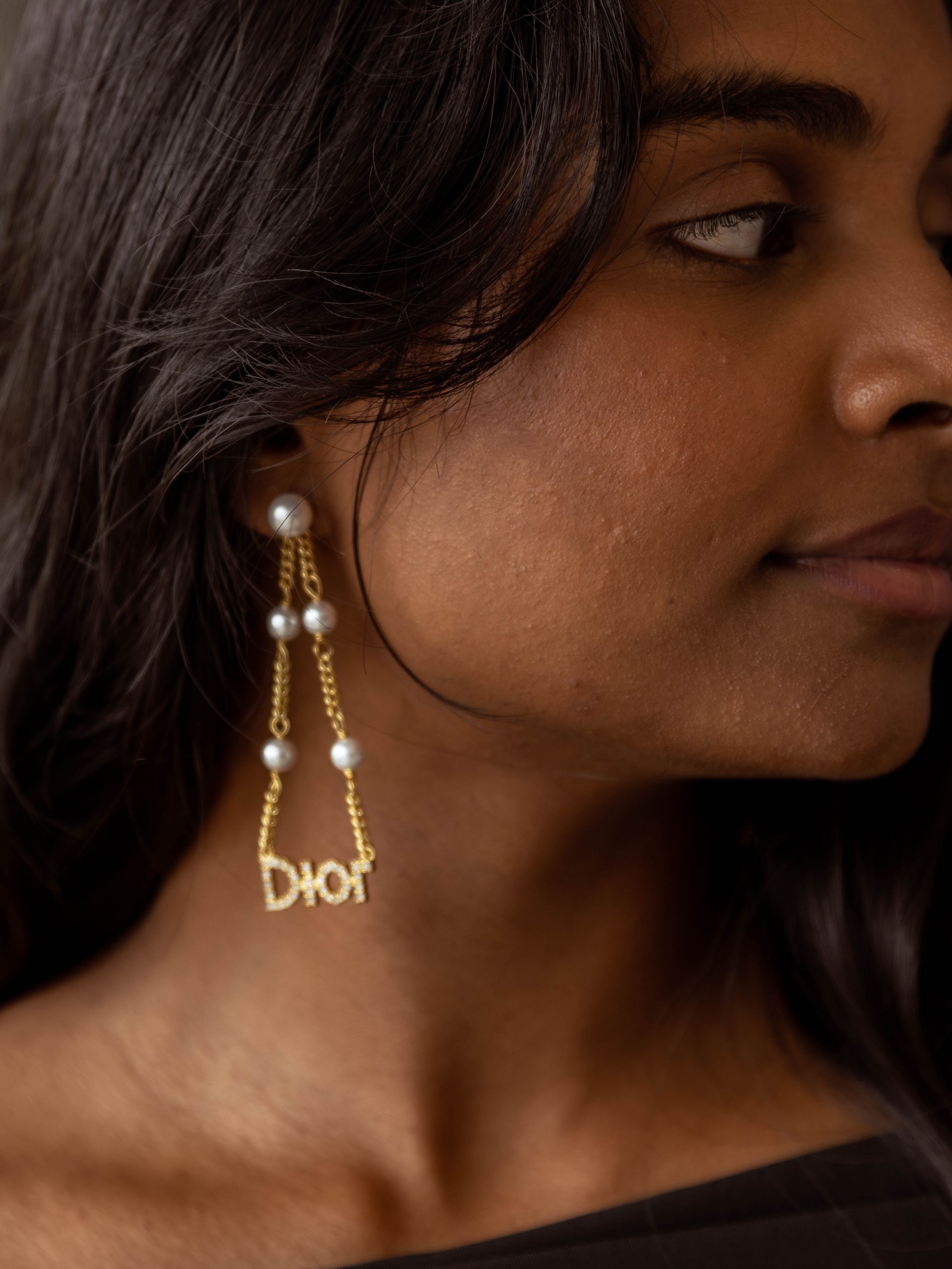 A woman wearing a pair of dior earrings with pearls
