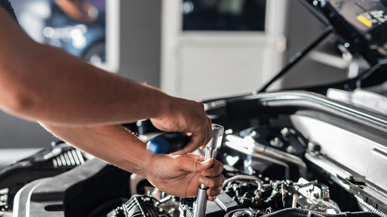 Mechanic working on a car engine with a wrench.