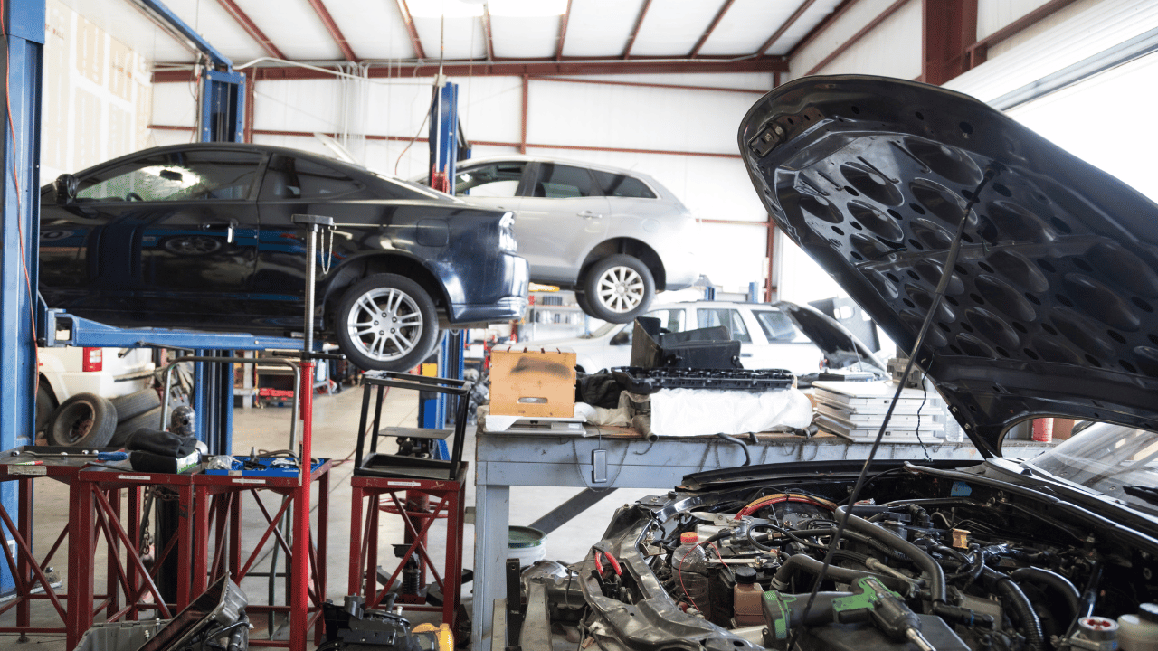 Cars being worked on in an auto repair shop with lifts and open hoods.