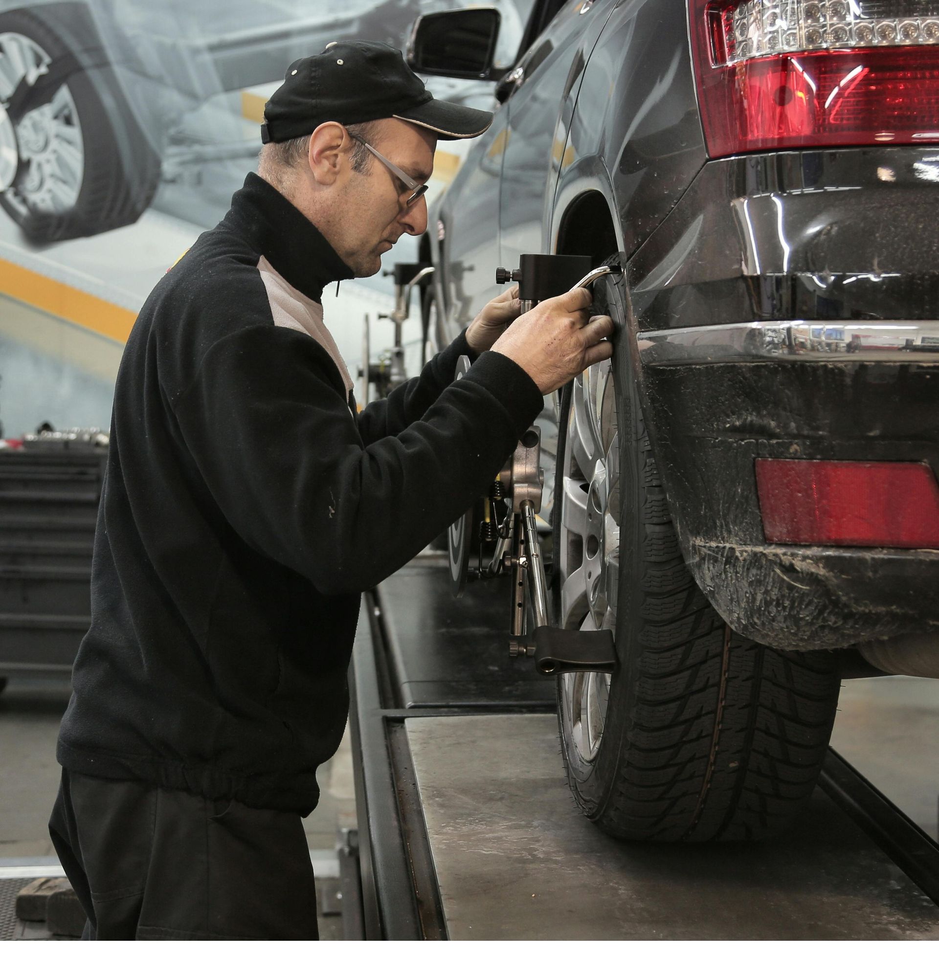 Mechanic adjusting car tire on a lift in a garage.