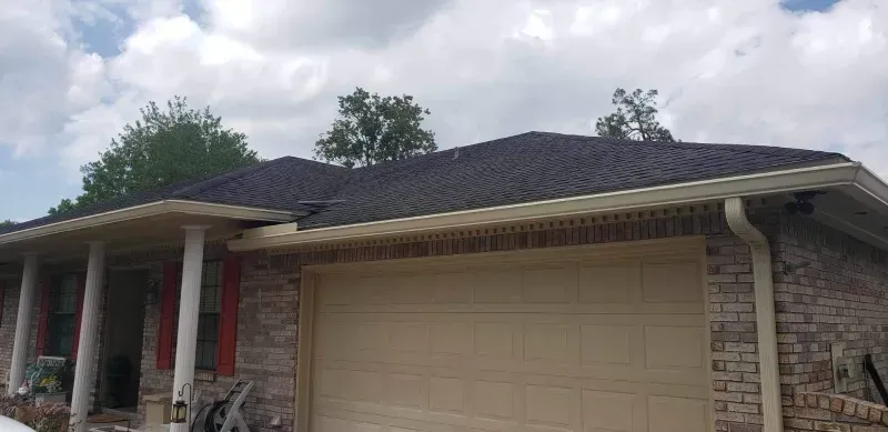 A brick house with a garage door and a black roof.