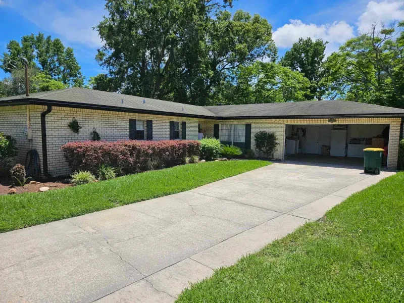 A white house with a green trash can in front of it