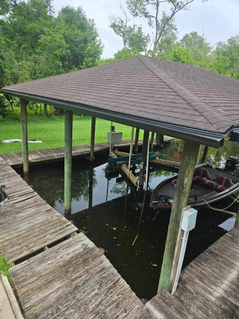 A boat is docked under a covered dock in the water.