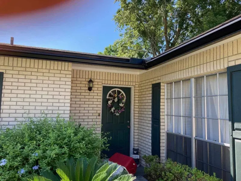 A white brick house with a green door and a wreath on the door.